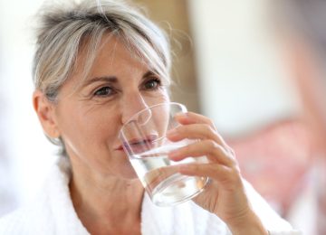 Mujer mayor bebiendo agua por la mañana