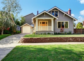 House exterior with front yard landscape. White entrance porch with railings and orange entrance door